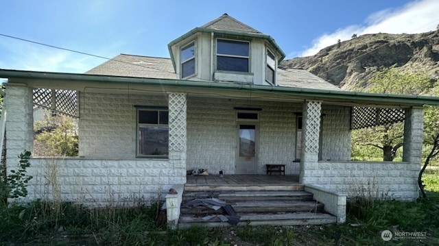 view of front facade featuring a porch, a mountain view, and roof with shingles