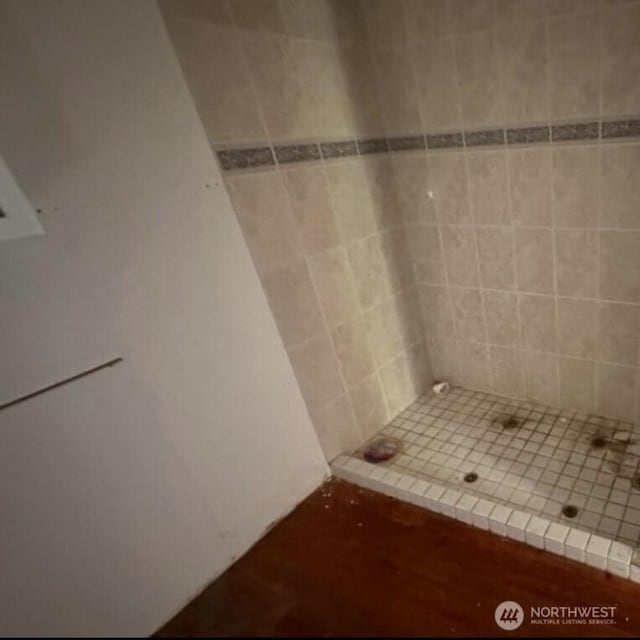 bathroom with wood finished floors and a shower stall