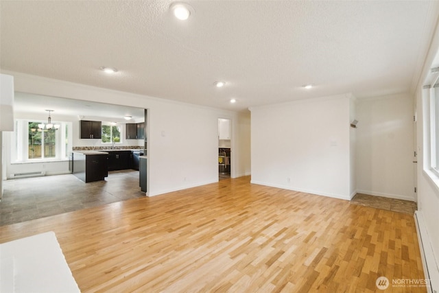 unfurnished living room featuring recessed lighting, baseboards, light wood-style flooring, and a baseboard radiator