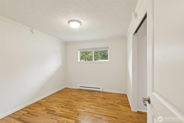 spare room with a baseboard radiator, light wood-style flooring, a textured ceiling, and ornamental molding
