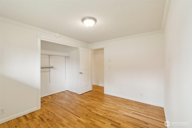 unfurnished bedroom with a closet, ornamental molding, wood finished floors, baseboards, and a textured ceiling