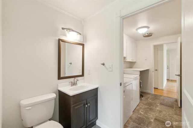 half bathroom with independent washer and dryer, crown molding, vanity, toilet, and baseboards