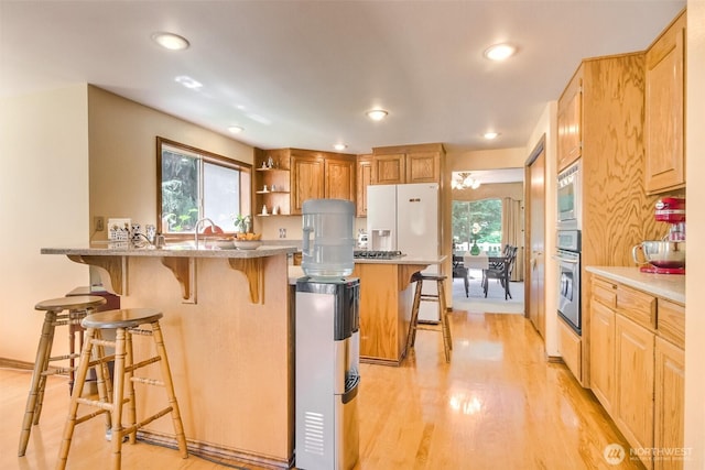 209 SW 331st Pl, Federal Way, WA 98023 - kitchen with oven, a kitchen breakfast bar, a peninsula, light wood-style flooring, and recessed lighting