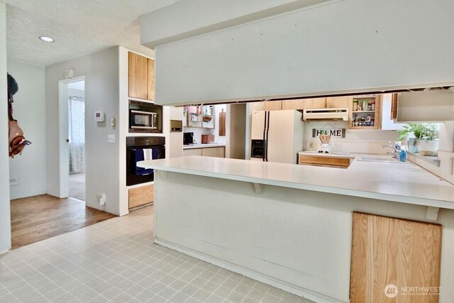 70 Shadow Trl, Sequim, WA 98382 - kitchen with black oven, a peninsula, white fridge with ice dispenser, under cabinet range hood, and light countertops