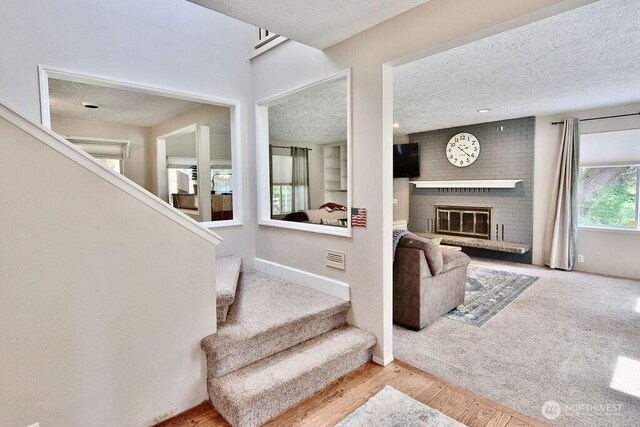 70 Shadow Trl, Sequim, WA 98382 - stairs with wood finished floors, a textured ceiling, visible vents, a fireplace, and baseboards