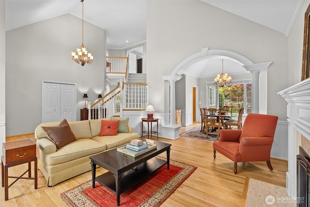 living room featuring an inviting chandelier, wood finished floors, high vaulted ceiling, stairway, and arched walkways