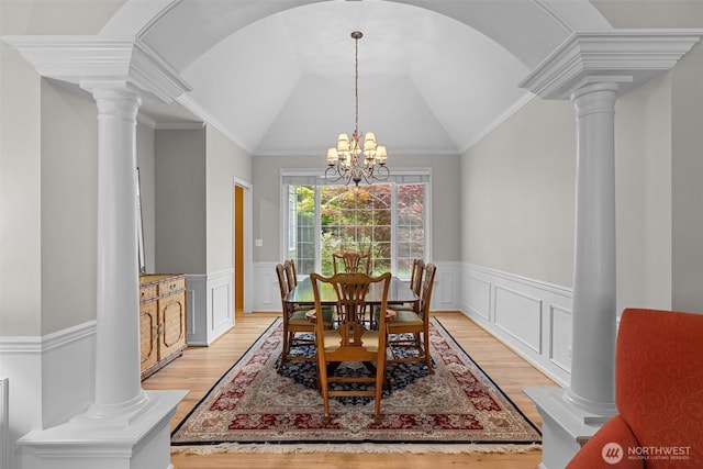 dining area featuring a wainscoted wall, decorative columns, light wood-type flooring, and a chandelier