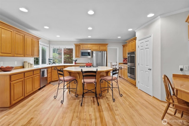 kitchen with a center island, ornamental molding, a breakfast bar, and stainless steel appliances