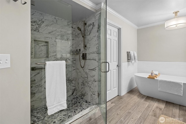 full bath with wainscoting, wood finished floors, a marble finish shower, ornamental molding, and a soaking tub