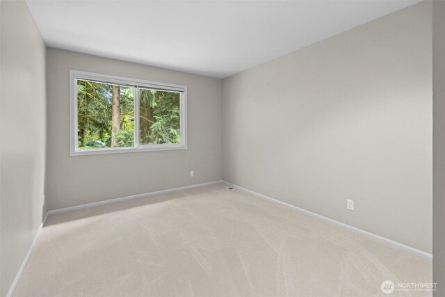 empty room featuring light colored carpet and baseboards