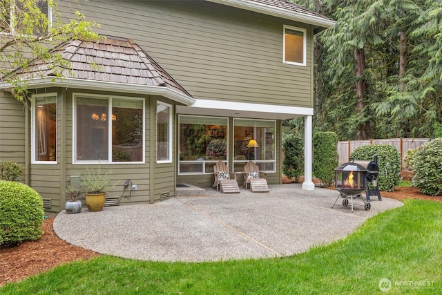rear view of house with fence, a patio, and an outdoor fire pit