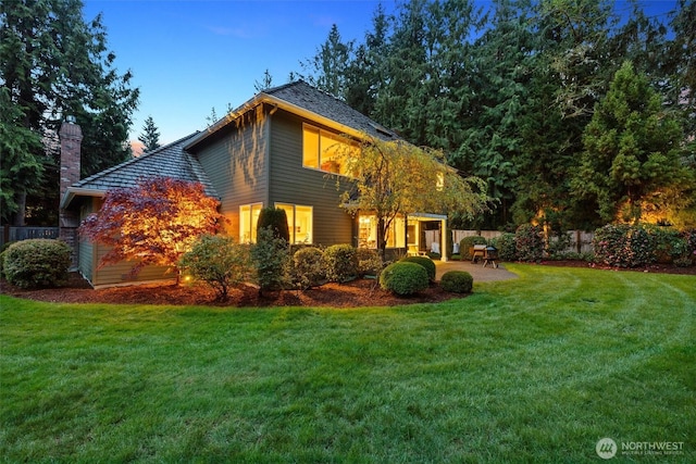 view of front facade featuring fence, a chimney, a patio area, and a front lawn