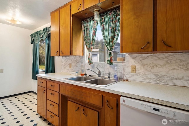 kitchen featuring decorative backsplash, light countertops, dishwasher, and a sink