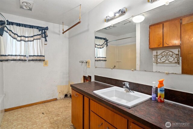 bathroom featuring a shower, vanity, and baseboards