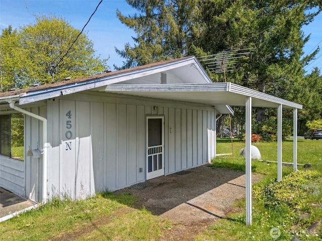 view of side of property featuring board and batten siding, a carport, and a yard