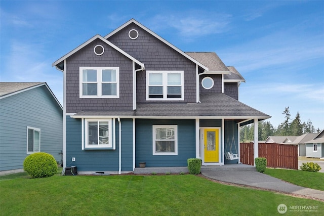 view of front of home with fence, a porch, a shingled roof, and a front yard