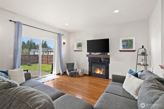 living area with recessed lighting, wood finished floors, and a glass covered fireplace