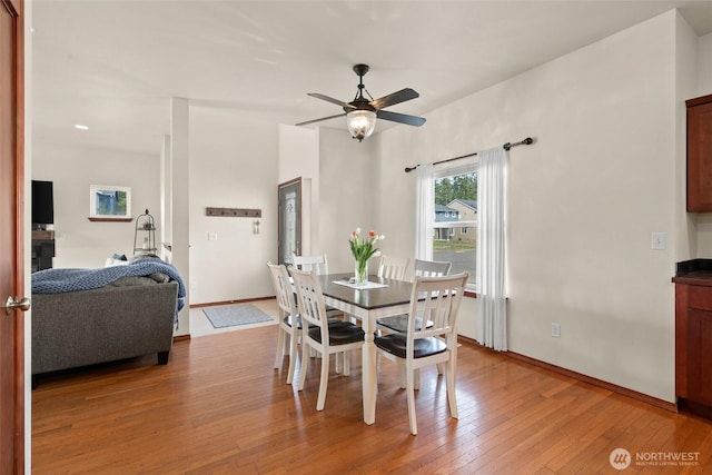 dining room featuring ceiling fan, baseboards, and light wood-style floors