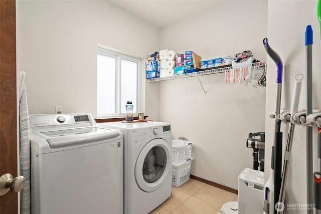 clothes washing area featuring baseboards, light tile patterned floors, washing machine and clothes dryer, and laundry area
