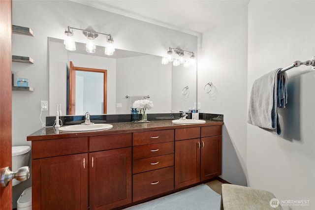 full bathroom with toilet, double vanity, and a sink