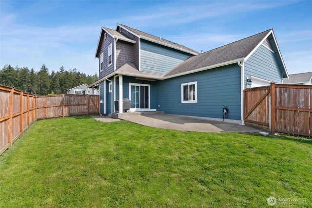 rear view of house featuring a patio, a lawn, and a fenced backyard