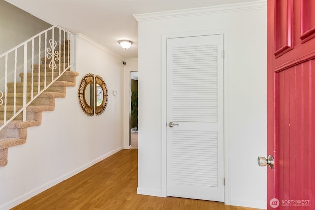 interior space featuring baseboards, ornamental molding, light wood-style flooring, and stairway