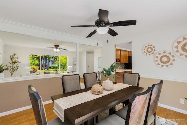 dining room featuring light wood-type flooring, ornamental molding, baseboards, and a ceiling fan