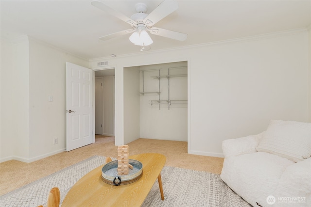 interior space with ceiling fan, carpet, ornamental molding, and visible vents