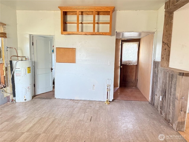 unfurnished room with water heater and wood finished floors