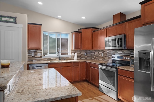 9321 179th Ln SW, Rochester, WA 98579 - kitchen featuring appliances with stainless steel finishes, a sink, light wood-style floors, decorative backsplash, and light stone countertops