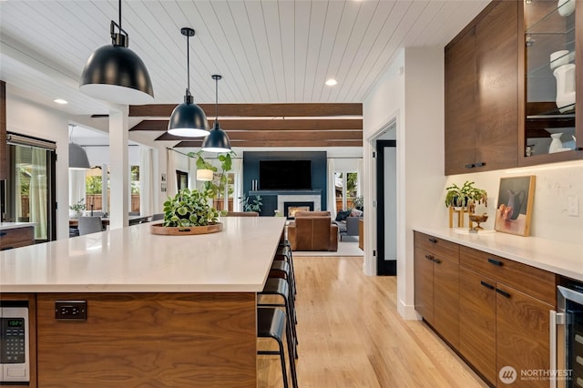 909 11th St, Mukilteo, WA 98275 - kitchen featuring modern cabinets, light wood-style floors, a kitchen bar, brown cabinetry, and open floor plan