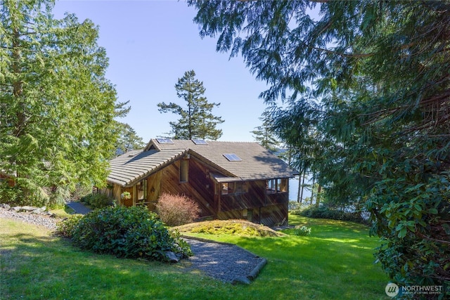 view of side of property with a tile roof and a lawn