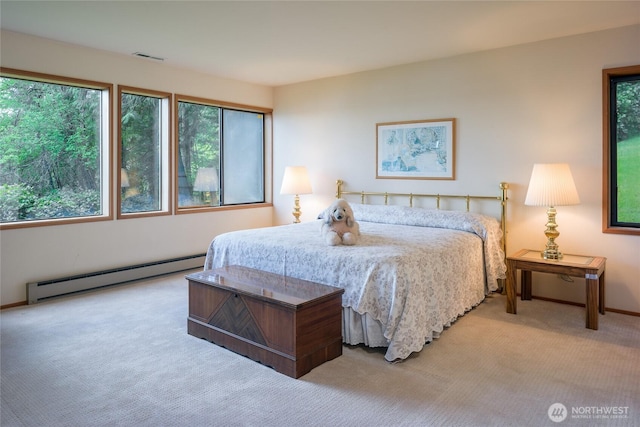 carpeted bedroom featuring a baseboard heating unit, visible vents, and baseboards