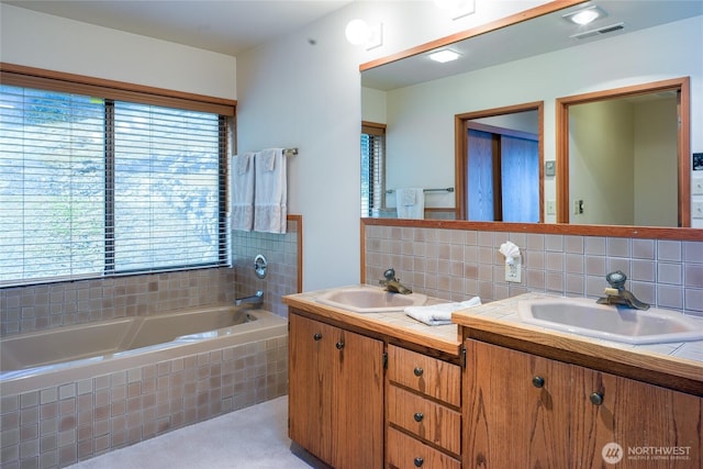 full bath featuring visible vents, tasteful backsplash, a bath, and a sink