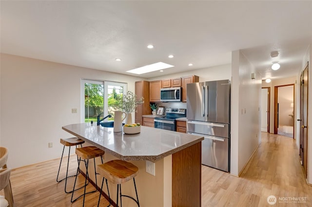 kitchen with light wood-style floors, a kitchen bar, recessed lighting, a center island, and appliances with stainless steel finishes