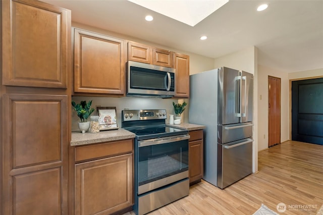 kitchen with a skylight, light countertops, stainless steel appliances, recessed lighting, and light wood-style flooring