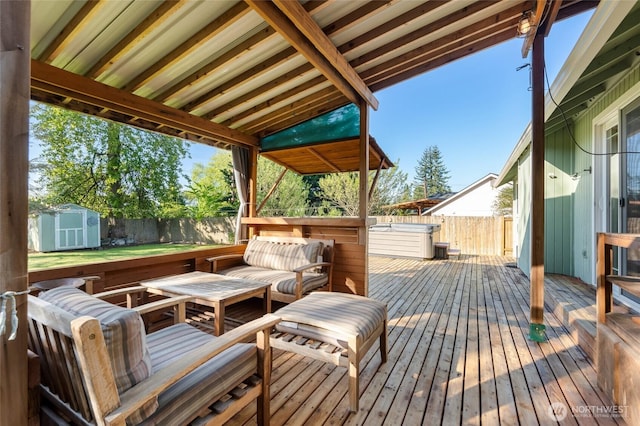 deck featuring an outdoor structure, a fenced backyard, a hot tub, and a shed
