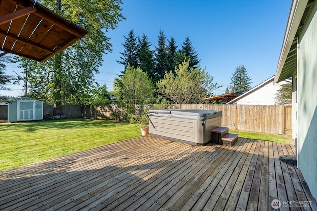wooden deck with an outbuilding, a hot tub, a fenced backyard, a storage unit, and a yard