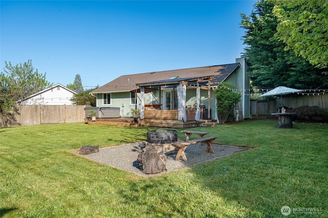 back of property with a fire pit, fence, a deck, a chimney, and a yard