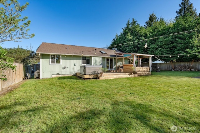 back of property featuring a lawn, a fenced backyard, a hot tub, and a patio area