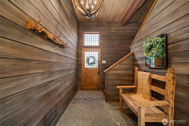 interior space with a chandelier, wood walls, and stone floors
