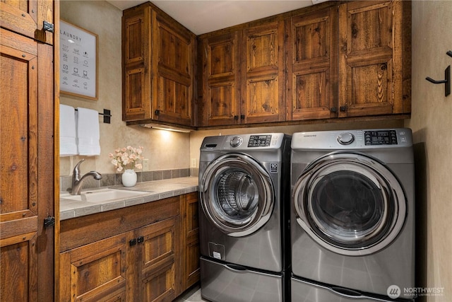 washroom featuring cabinet space, washing machine and clothes dryer, and a sink