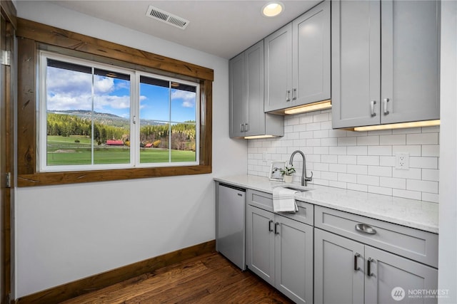 kitchen with visible vents, gray cabinetry, dark wood finished floors, and backsplash