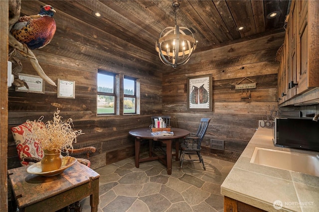 dining space with recessed lighting, wooden ceiling, a chandelier, stone finish floor, and wood walls