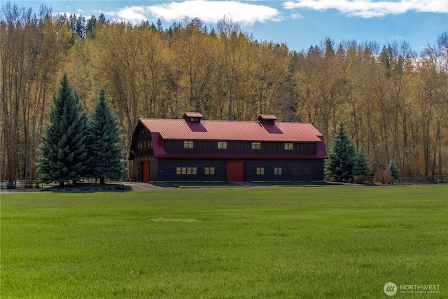 view of front of property with a barn, a front yard, and a view of trees