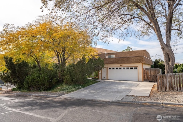 view of front of property featuring fence, a shingled roof, mansard roof, concrete driveway, and an attached garage