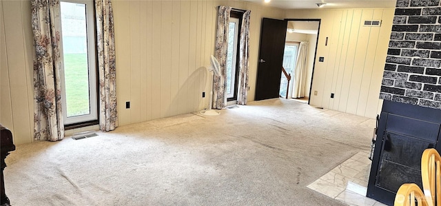 spare room featuring visible vents, wood walls, and carpet