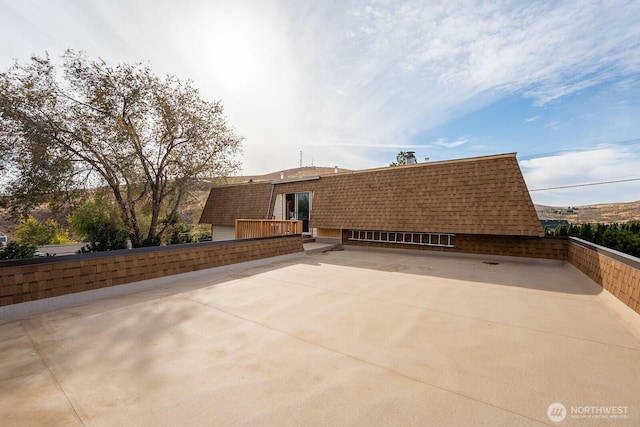 rear view of property featuring roof with shingles and a patio area