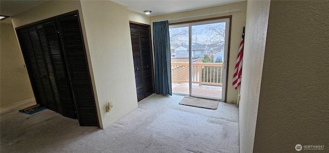 doorway to outside featuring carpet flooring and a textured wall