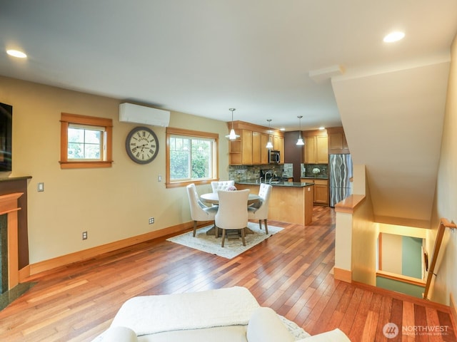 living room featuring a fireplace, baseboards, a wall mounted air conditioner, light wood-type flooring, and recessed lighting
